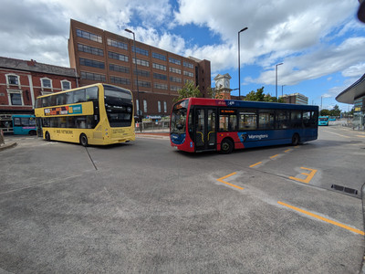 A bright yellow double deck bus and another blue bus leaving the Interchange